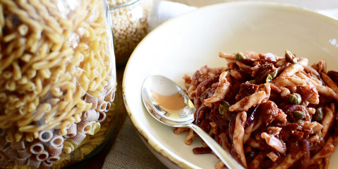 Pasta e basta! | © SONNENTOR Auf dem Foto sieht man einen Teller mit Pasta. Daneben sieht man ein Glas gefüllt mit den ungekochten Teigwaren. | © SONNENTOR
