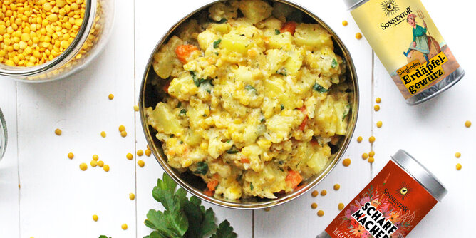 Gelbes Curry | © SONNENTOR Auf dem Foto ist eine Schale mit gelben Curry zu sehen. Daneben sieht man eine Dose Sieglindes Erdäpfelgewürz und eine Dose Scharfmacher Gewürzblüten. | © SONNENTOR