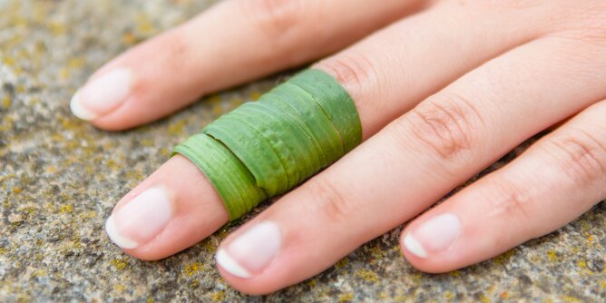 Spitzwegerich | © SONNENTOR Auf dem Foto sieht man eine Hand. Um einen Finger ist Spitzwegerich gewickelt. | © SONNENTOR